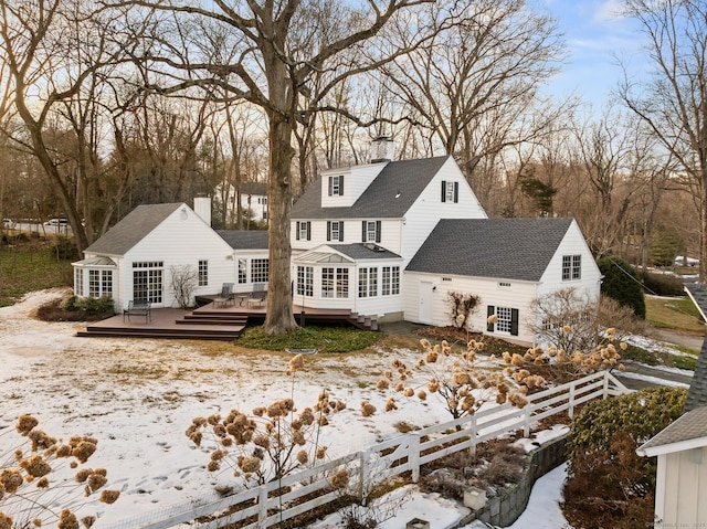 rear view of house featuring a chimney, fence, a deck, and roof with shingles