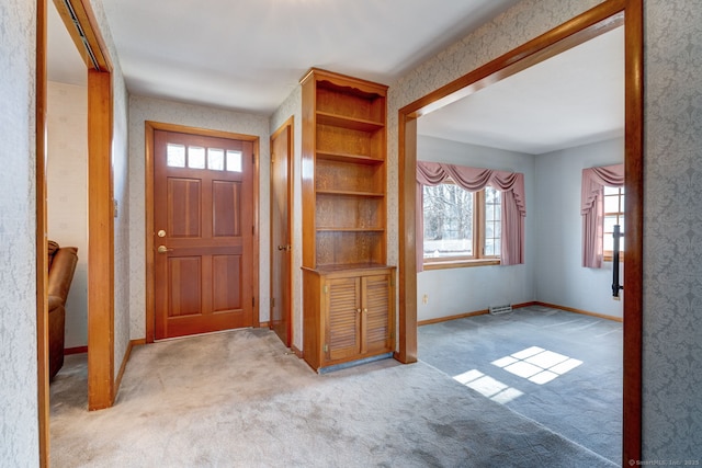 foyer entrance featuring carpet and baseboards