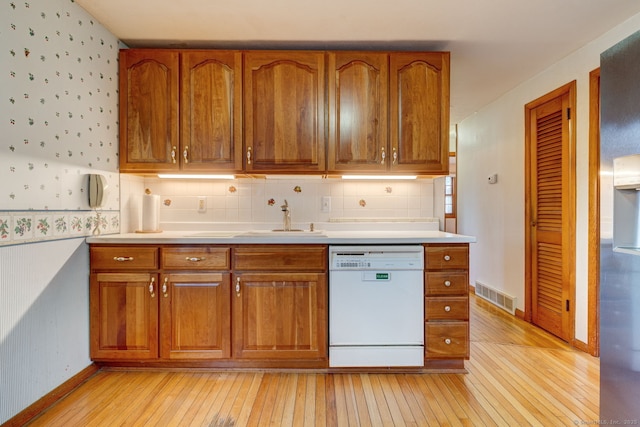 kitchen with a sink, visible vents, brown cabinets, and dishwasher