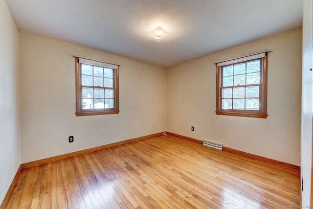 spare room featuring baseboards, visible vents, and light wood-type flooring