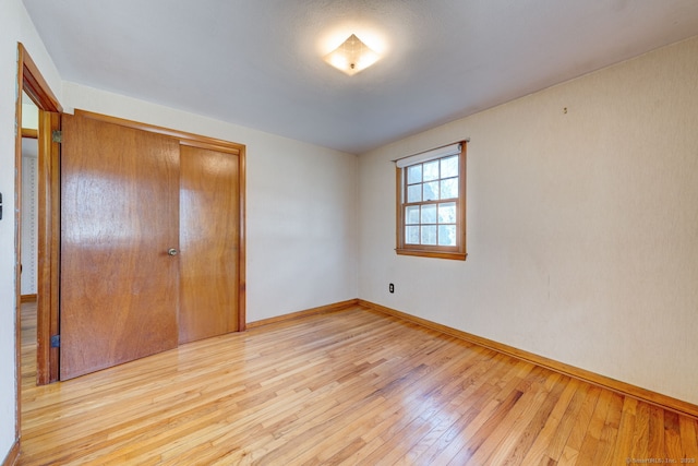 unfurnished bedroom with baseboards, a closet, and light wood finished floors