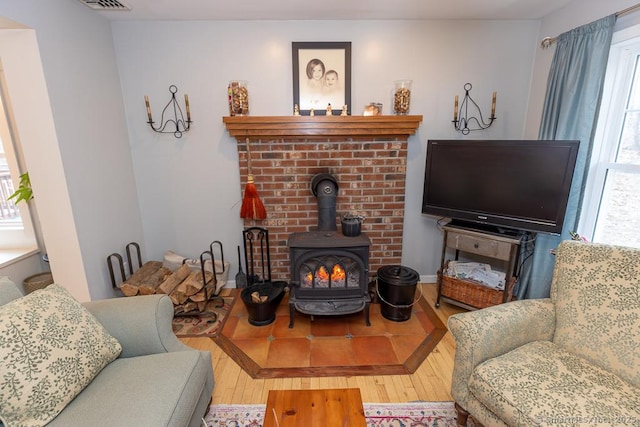 living room featuring a wood stove, visible vents, and wood finished floors