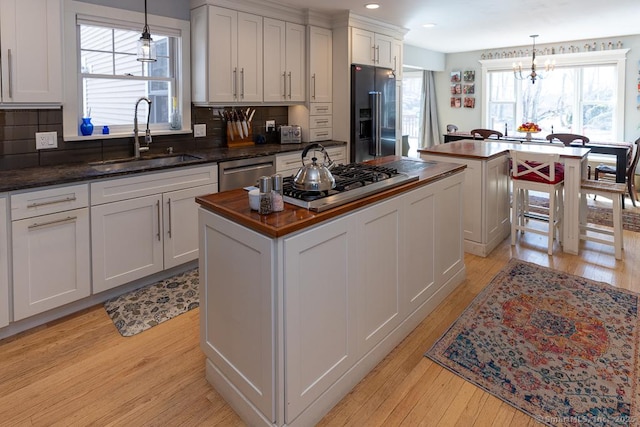 kitchen with light wood finished floors, stainless steel appliances, a sink, and a center island