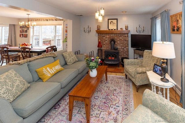 living room featuring visible vents, a baseboard radiator, wood finished floors, a wood stove, and a chandelier