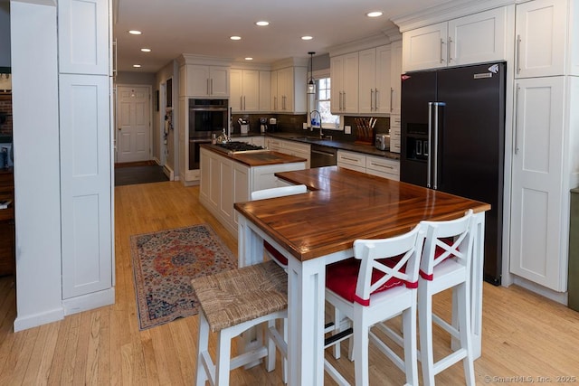 kitchen featuring dishwasher, an island with sink, high end black fridge, double oven, and a sink