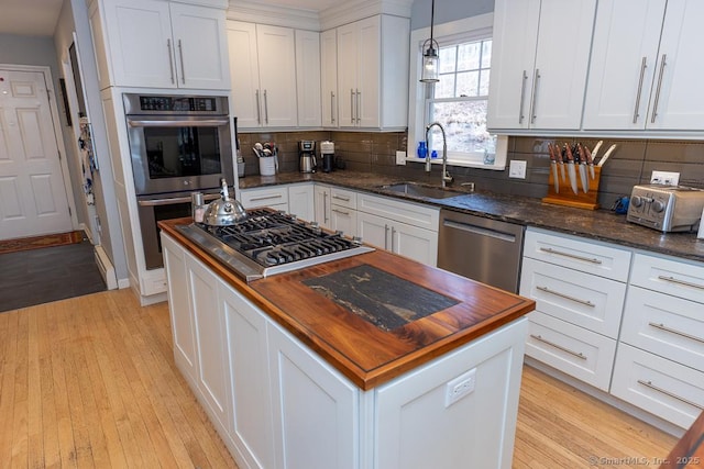 kitchen featuring appliances with stainless steel finishes, butcher block countertops, a sink, and a center island