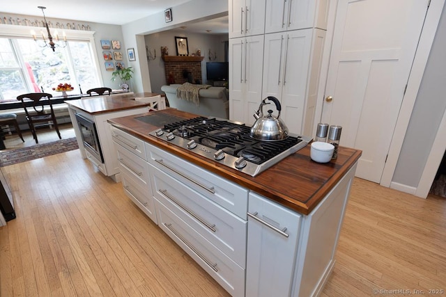 kitchen featuring butcher block countertops, white cabinets, stainless steel gas stovetop, and light wood-style flooring