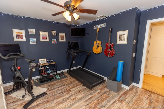 workout area with baseboards, ceiling fan, visible vents, and wood finished floors