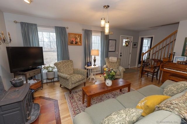 living room with a baseboard heating unit, a healthy amount of sunlight, light wood-style flooring, and stairs