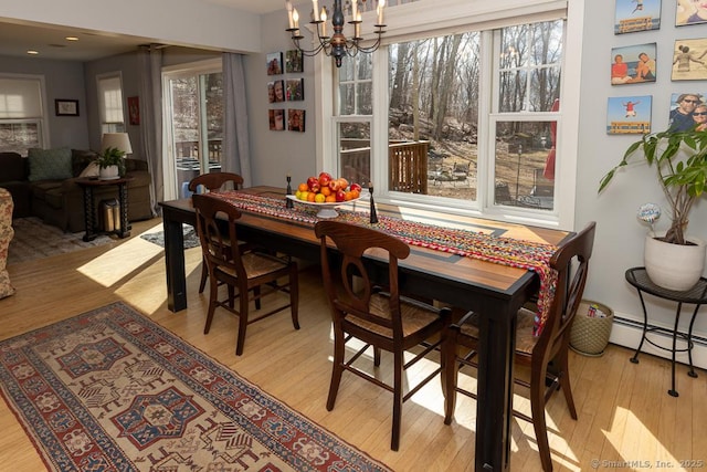 dining room featuring light wood-style floors, a chandelier, and baseboard heating