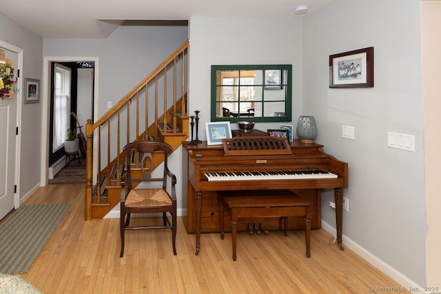 interior space with a baseboard radiator, stairway, baseboards, and wood finished floors