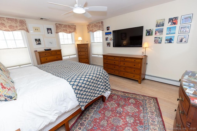 bedroom with a baseboard heating unit, a ceiling fan, visible vents, and wood finished floors