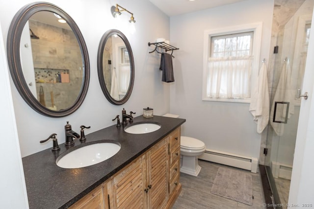 bathroom featuring a stall shower, a sink, baseboard heating, and double vanity