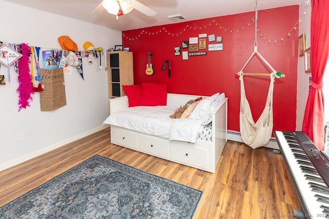 bedroom with baseboards, visible vents, and wood finished floors