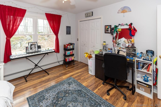 office with a ceiling fan, a baseboard radiator, and wood finished floors