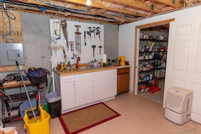 unfinished basement with electric panel, light floors, and a workshop area