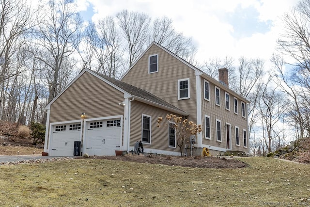 exterior space featuring a garage, driveway, and a chimney