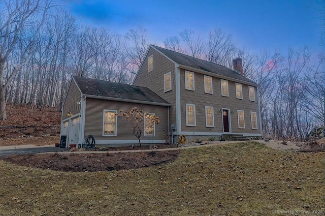 colonial-style house featuring an attached garage and a chimney