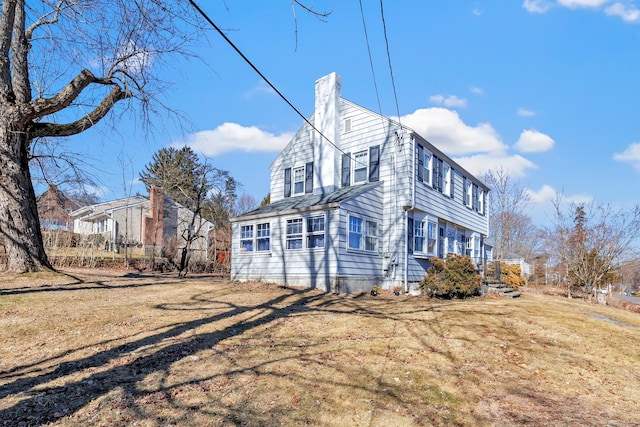 view of home's exterior featuring a chimney and a lawn