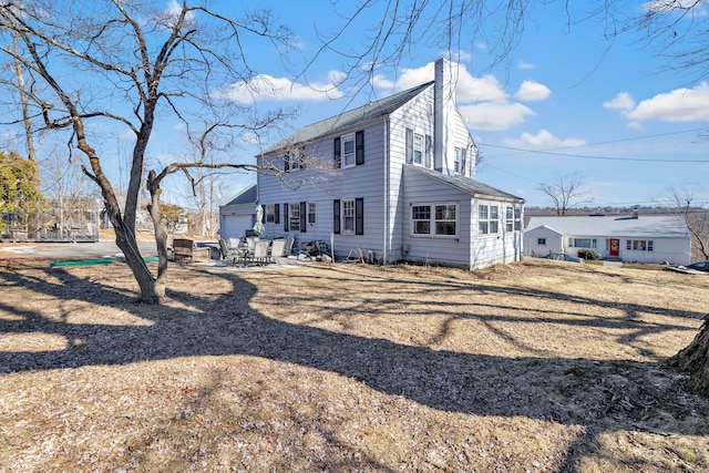 back of property featuring driveway and a chimney