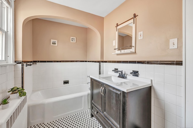 bathroom with a wainscoted wall, a garden tub, tile walls, radiator, and vanity