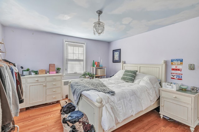 bedroom featuring a notable chandelier and light wood finished floors