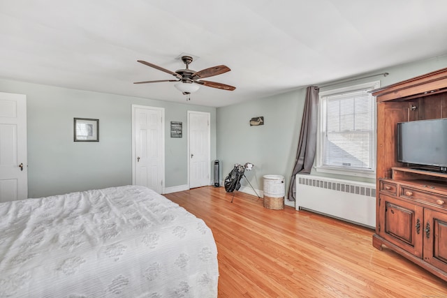 bedroom with ceiling fan, baseboards, multiple closets, light wood-type flooring, and radiator