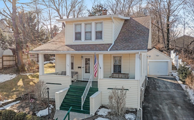 view of front facade featuring driveway, a detached garage, roof with shingles, an outdoor structure, and a porch