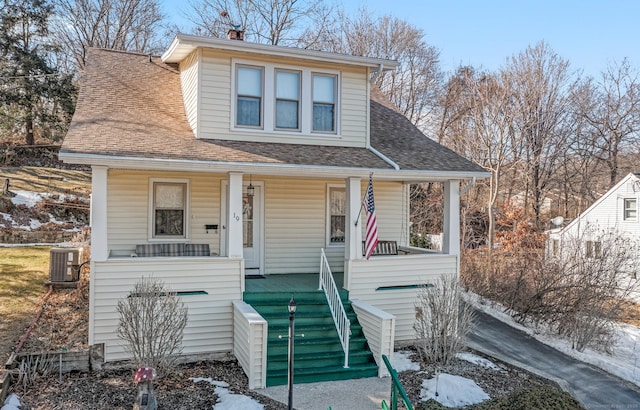 bungalow with a porch, roof with shingles, and cooling unit