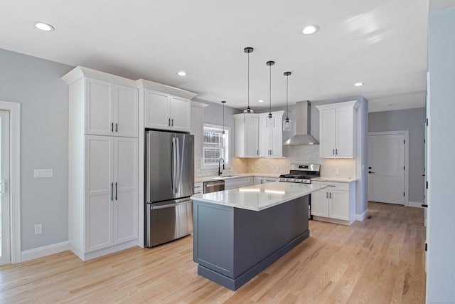 kitchen featuring stainless steel appliances, white cabinetry, wall chimney range hood, light wood-type flooring, and decorative backsplash