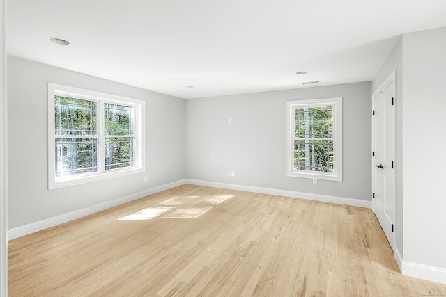 unfurnished room with light wood-style floors, plenty of natural light, and baseboards