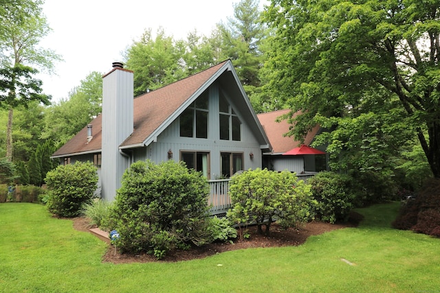 back of property with a lawn, a chimney, and a shingled roof