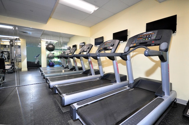 workout area with a drop ceiling, visible vents, and baseboards