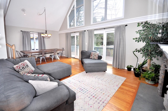 living area with a notable chandelier, light wood-style flooring, and high vaulted ceiling