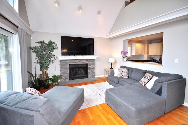 living room with a fireplace, light wood-style floors, and high vaulted ceiling