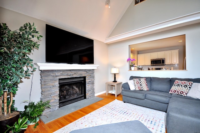 living area with a fireplace, light wood-type flooring, and high vaulted ceiling