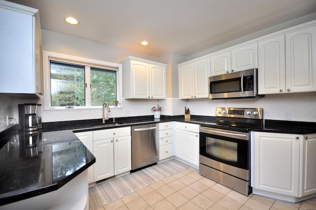 kitchen featuring a sink, backsplash, appliances with stainless steel finishes, and white cabinetry