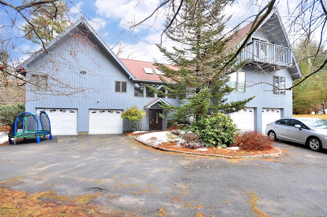 exterior space featuring aphalt driveway, a balcony, and a garage