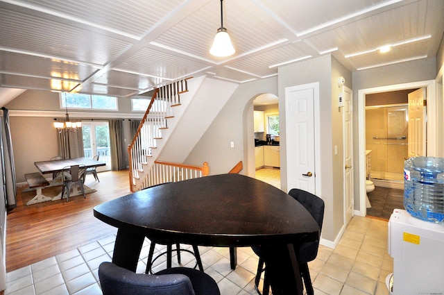 dining room featuring an inviting chandelier, stairway, light tile patterned floors, and arched walkways