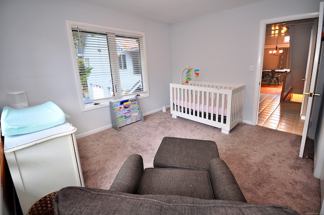 bedroom featuring a crib, carpet floors, tile patterned flooring, baseboards, and a chandelier