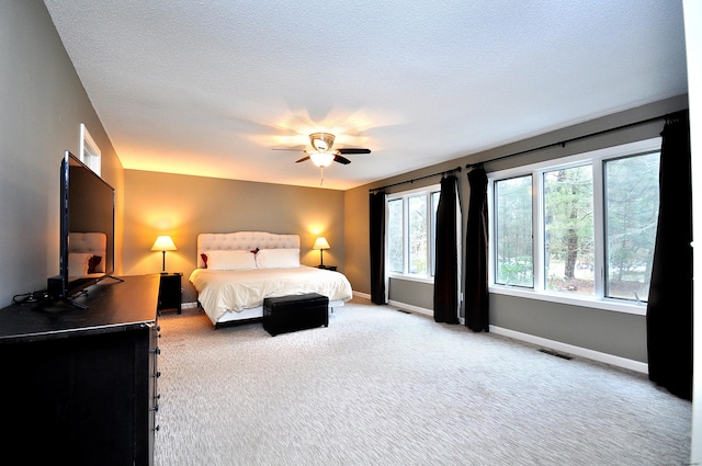 carpeted bedroom with ceiling fan, visible vents, baseboards, and a textured ceiling