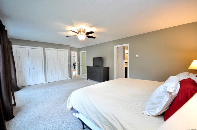 carpeted bedroom with baseboards, two closets, and ceiling fan