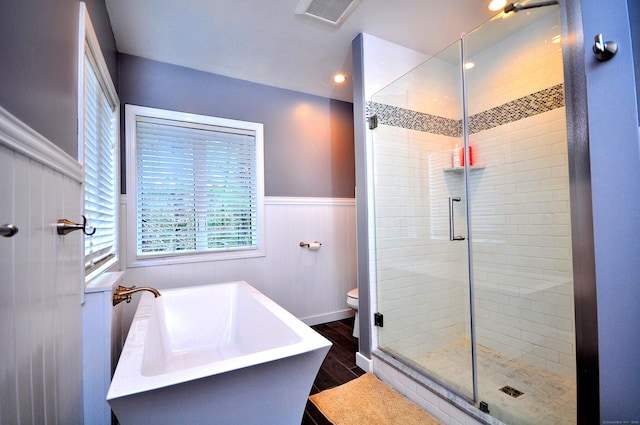 bathroom with visible vents, wainscoting, a stall shower, and wood finished floors