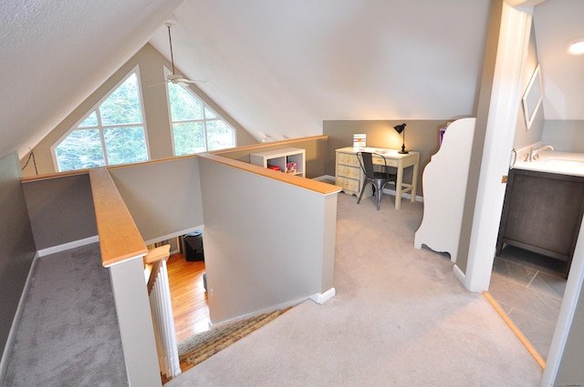 interior space with vaulted ceiling, carpet flooring, an upstairs landing, and a sink