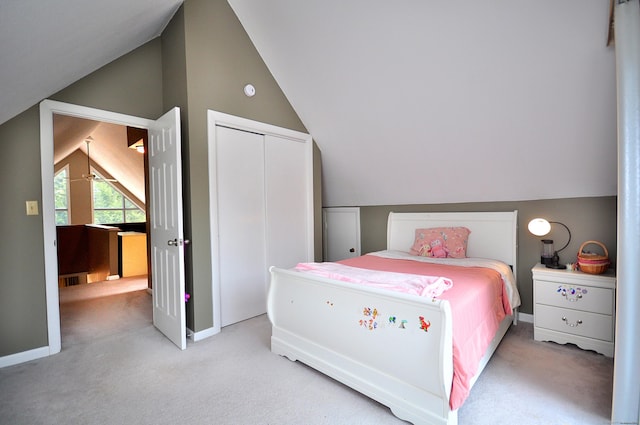 bedroom featuring a closet, light colored carpet, baseboards, and lofted ceiling