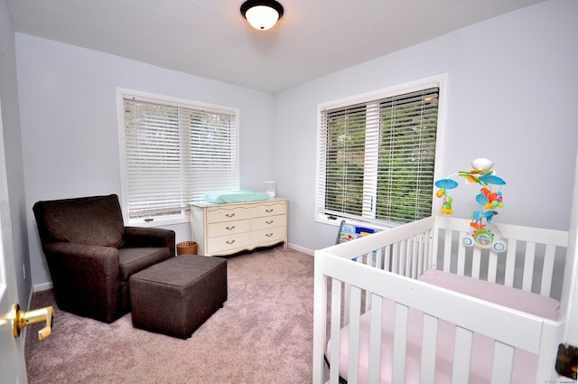 bedroom with baseboards, a nursery area, and carpet flooring