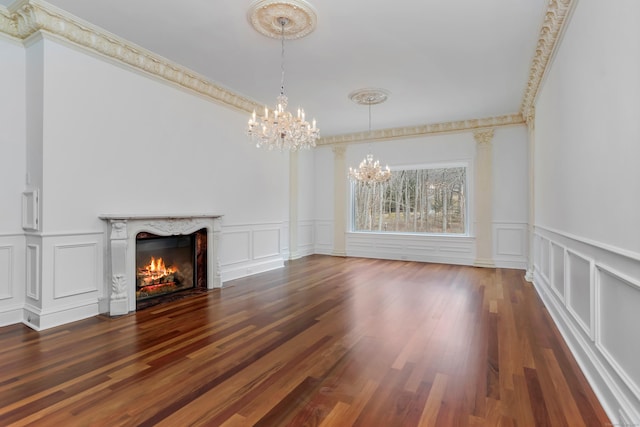 unfurnished living room with a notable chandelier, wood finished floors, a high end fireplace, and a decorative wall