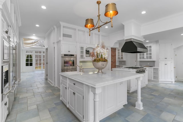 kitchen with ornamental molding, a sink, a large island, oven, and white cabinetry