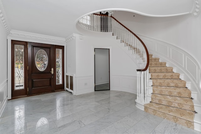 foyer featuring stairway, a decorative wall, and marble finish floor