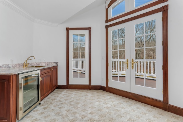 interior space with light stone countertops, beverage cooler, a sink, french doors, and light carpet